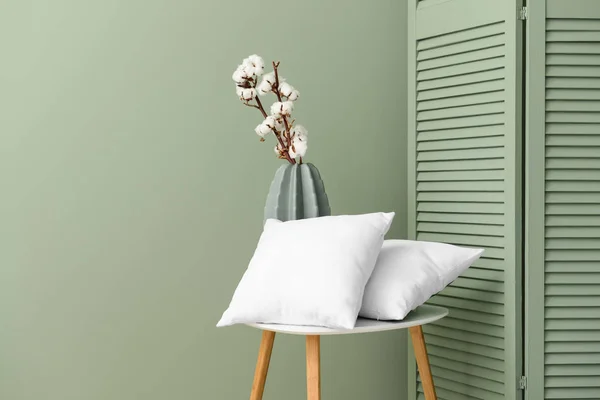 柔らかい枕と花瓶と色の壁の近くに綿の花が付いているテーブル — ストック写真