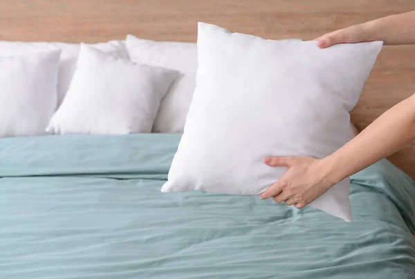 Mujer esponjando almohadas suaves en la cama —  Fotos de Stock