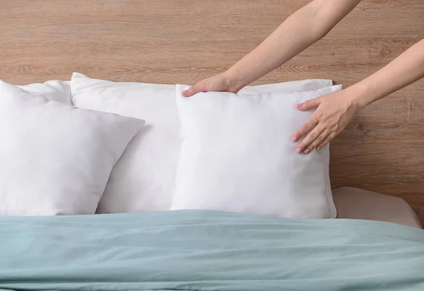 Женщина взбивает мягкие подушки на кровати — стоковое фото