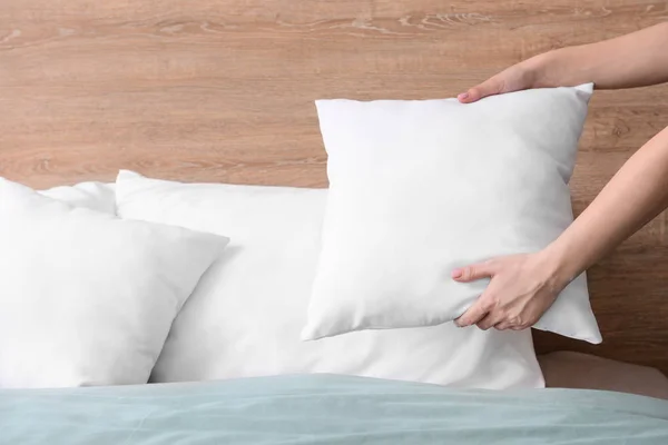 ベッドの上で柔らかい枕をふくらませる女性 — ストック写真