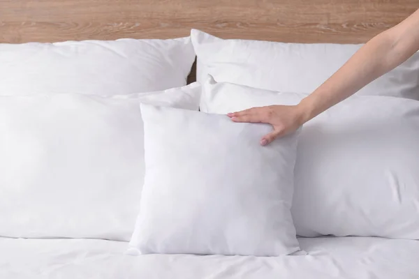 Woman fluffing soft pillows on bed — Stock Photo, Image