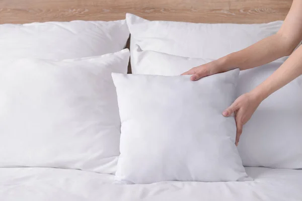 Woman fluffing soft pillows on bed — Stock Photo, Image