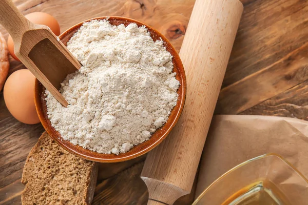 Bowl with flour and products on wooden background — Stock Photo, Image