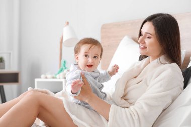 Evde yatakta sevimli erkek bebek ile Mutlu anne