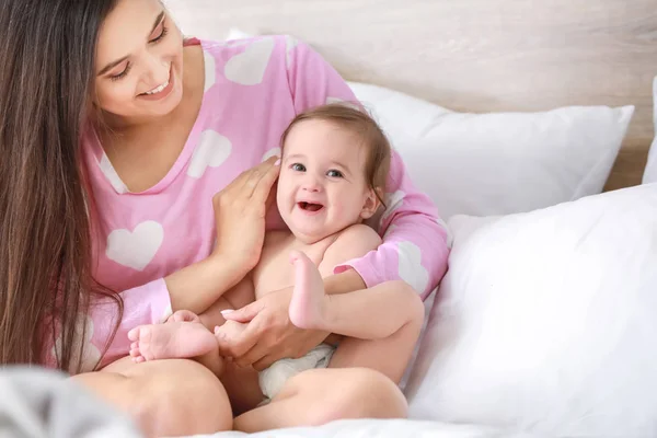 Madre feliz con adorable bebé niño sentado en la cama en casa —  Fotos de Stock