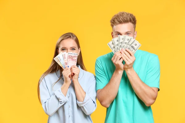 Young couple with money on color background — Stock Photo, Image