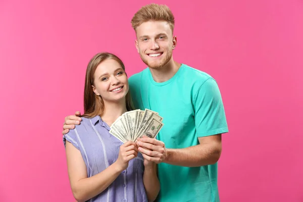 Happy couple with money on color background — Stock Photo, Image