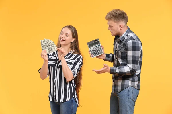Hombre problemático con calculadora y mujer feliz con dinero en el fondo de color —  Fotos de Stock
