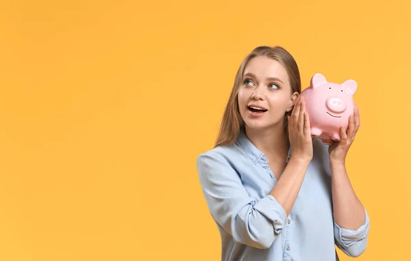 Jovem com banco porquinho no fundo de cor — Fotografia de Stock