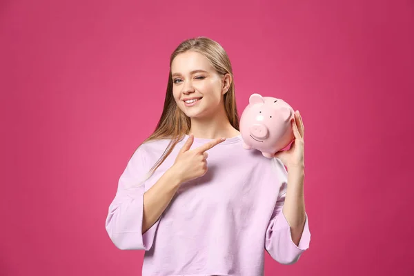 Happy woman with piggy bank on color background — Stock Photo, Image