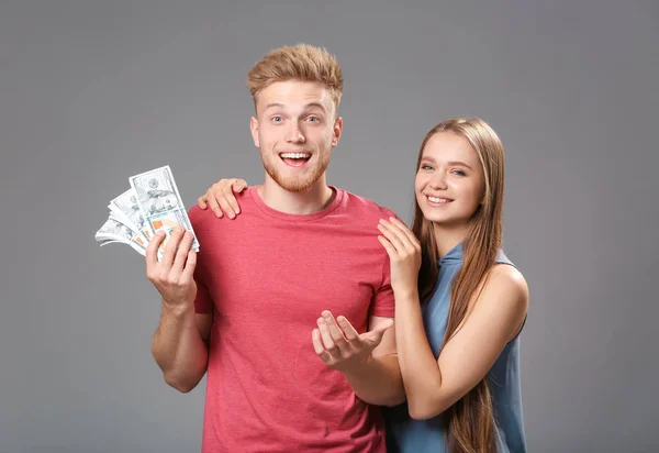Happy couple with money on grey background