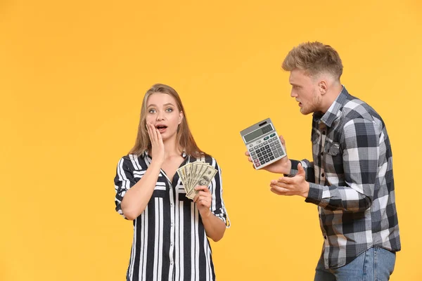 Troubled couple with money and calculator on color background — Stock Photo, Image