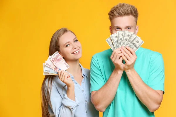 Happy couple with money on color background — Stock Photo, Image