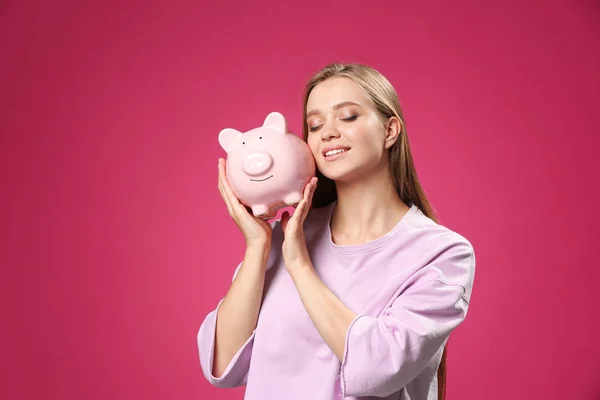 Mulher feliz com banco porquinho no fundo de cor — Fotografia de Stock