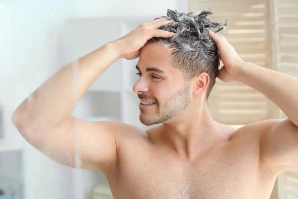 Handsome man washing hair in bathroom