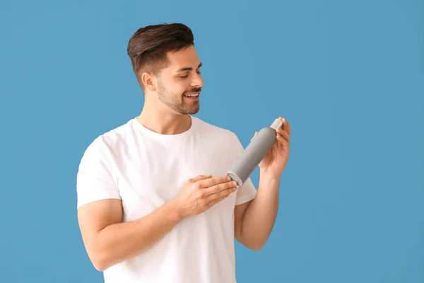 Handsome man with bottle of shampoo on color background — Stock Photo, Image