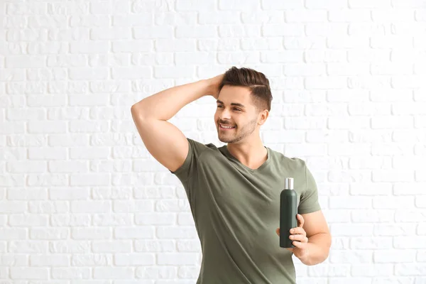 Handsome man with bottle of shampoo on white background — Stock Photo, Image