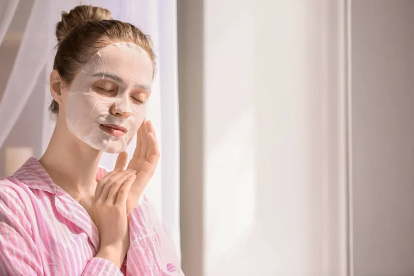 Young woman with sheet facial mask at home — Stock Photo, Image