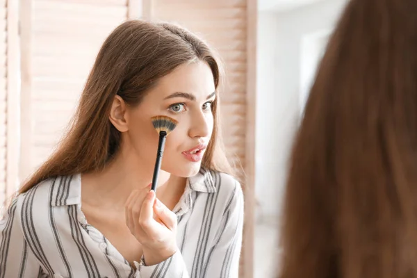 Mujer joven cerca del espejo en la sala de maquillaje — Foto de Stock