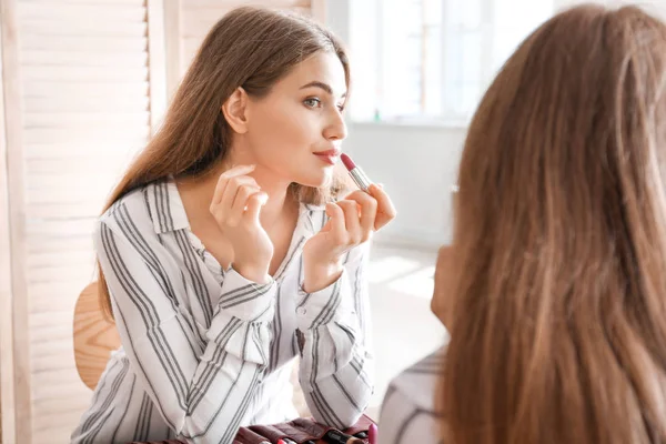 Mujer joven cerca del espejo en la sala de maquillaje — Foto de Stock