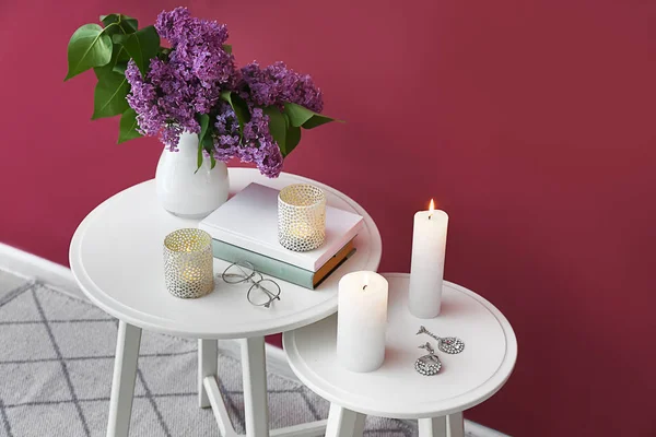 Beautiful burning candles with lilac flowers on tables in room — Stock Photo, Image