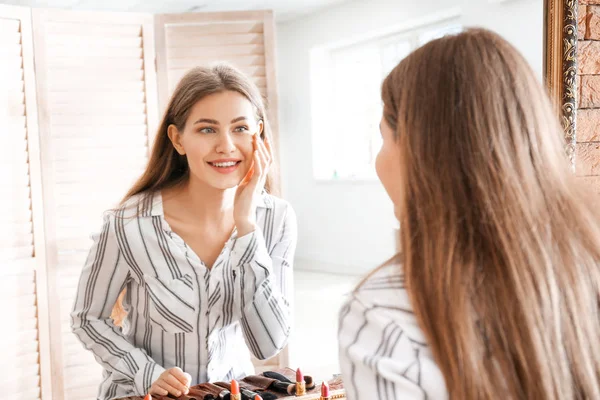 Mujer joven cerca del espejo en la sala de maquillaje — Foto de Stock
