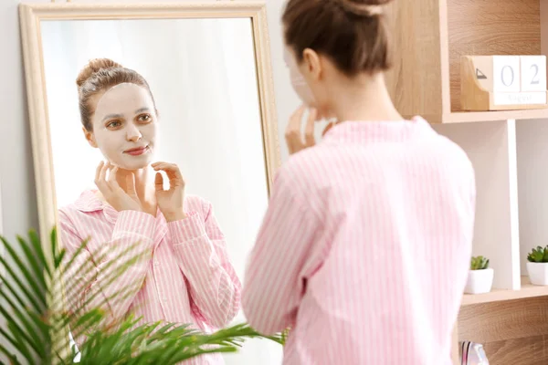 Young woman with sheet facial mask at home — Stock Photo, Image