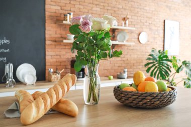 Mutfak masasında meyve, ekmek ve çiçek ile Kase