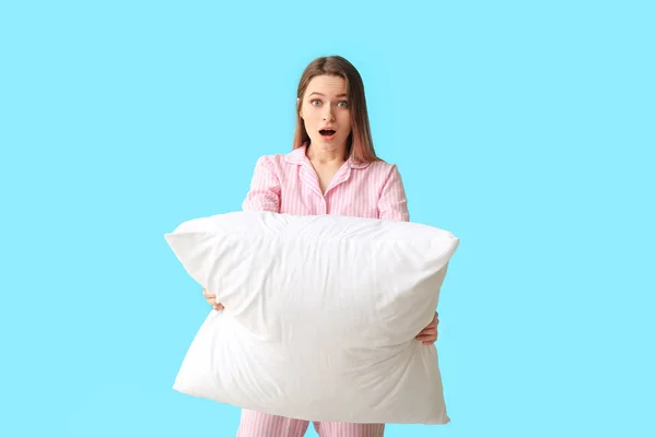 Surprised young woman with pillow on color background — Stock Photo, Image