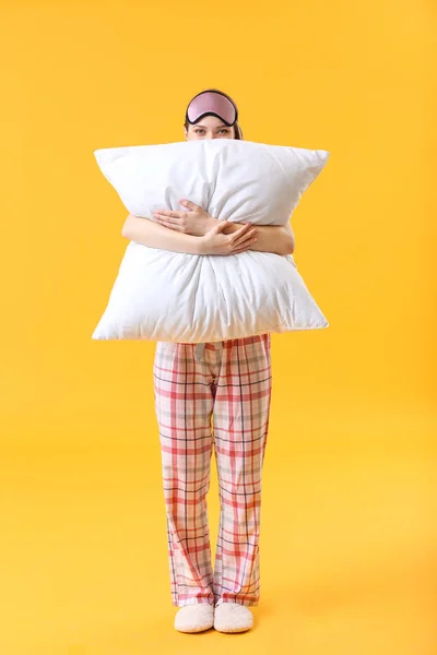 Jonge vrouw met kussen en slaapmasker op kleur achtergrond — Stockfoto