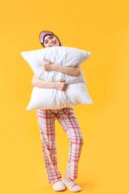 Renk arka planda yastık ve uyku maskesi ile genç kadın