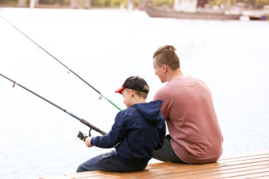 Baba ve oğul nehirde birlikte balık tutuyorlar.