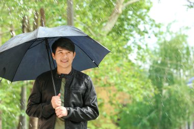 Yağmurlu günde şemsiye açık havada yakışıklı Asyalı adam