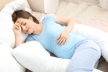 Hamile yastığı evde uyuyan genç hamile kadın