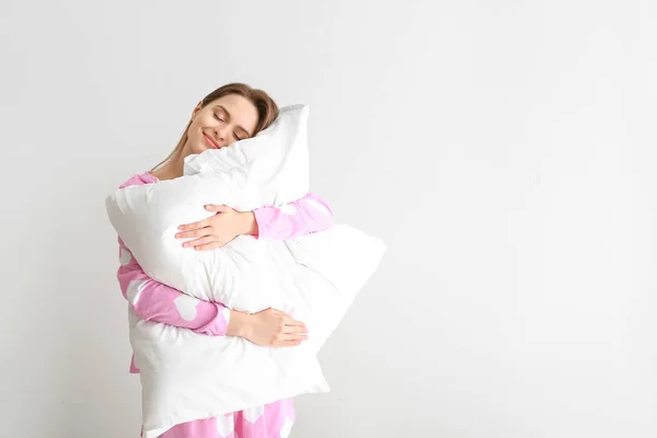 Jeune femme avec des oreillers sur fond blanc — Photo