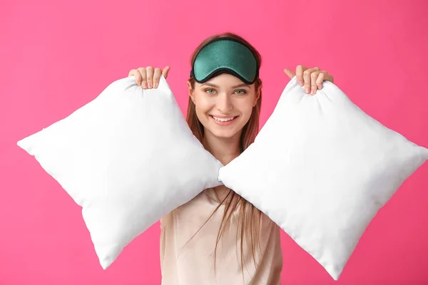 Young woman with pillows and sleep mask on color background — Stock Photo, Image