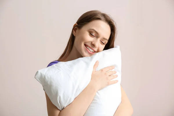 Młoda kobieta z poduszką na jasnym tle — Zdjęcie stockowe