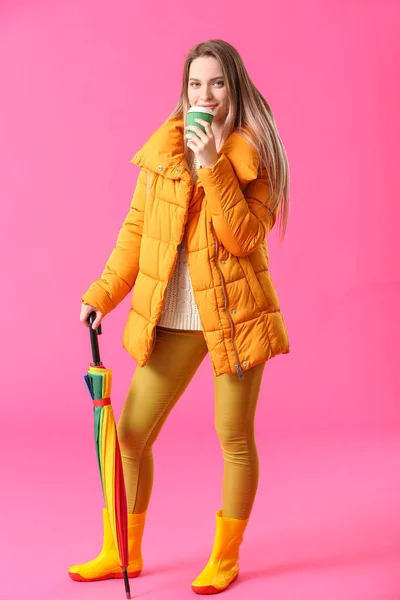 Krásná mladá žena s deštníkem a kávou na pozadí barev — Stock fotografie