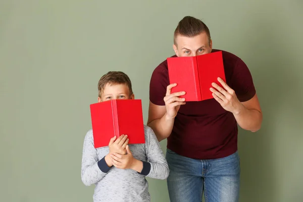 Porträt von Vater und Sohn mit Büchern auf farbigem Hintergrund — Stockfoto