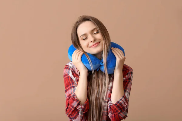 Young woman with travel pillow on color background — Stock Photo, Image