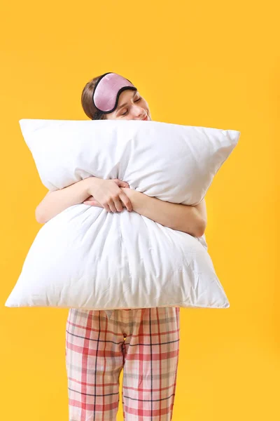 Giovane donna con cuscino e maschera del sonno su sfondo di colore — Foto Stock