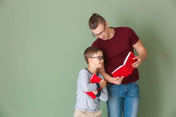 Retrato de pai e filho com livros sobre fundo de cor — Fotografia de Stock