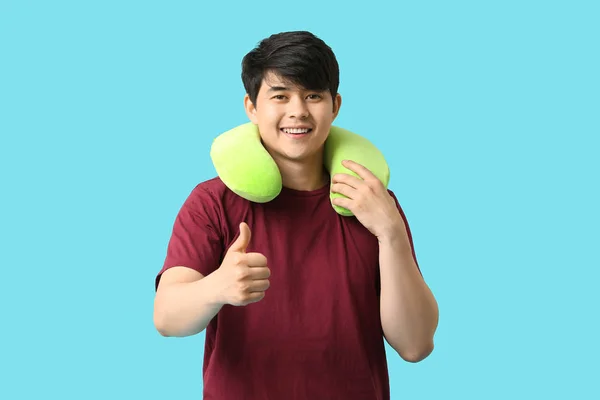 Handsome young man with travel pillow on color background — Stock Photo, Image