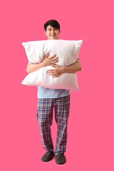 Handsome young man with pillow on color background