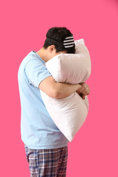 Schöner junger Mann mit Schlafmaske und Kopfkissen auf farbigem Hintergrund — Stockfoto