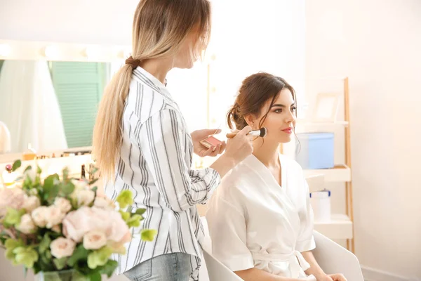 Professional makeup artist working with young bride at home — Stock Photo, Image