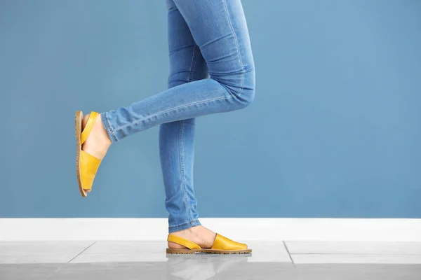 Jonge vrouw in stijlvolle schoenen tegen kleur muur — Stockfoto