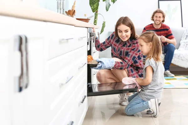 Giovane donna e la sua piccola figlia cuocere gustosi muffin a casa — Foto Stock