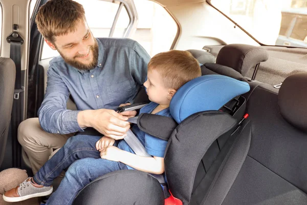 Отец пристегивает своего ребенка на автомобильном сидении — стоковое фото