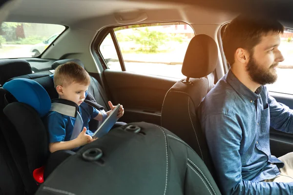 Мужчина за рулём машины с сыном, пристегнутым к детскому креслу — стоковое фото